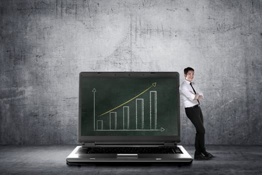 Asian business man leaning on big laptop, show report