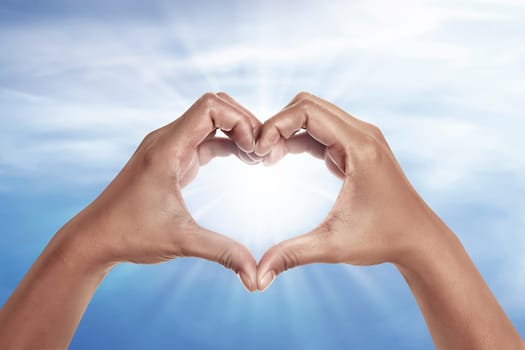 heart shaped hand with blue sky background. heart shaped hand is a symbol of love, freedom, romance