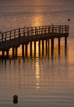 Beautiful sunrise in the summer over old wooden bridge and silent glossy sea. Sunrise over the sea. Pier on the foreground. Panorama