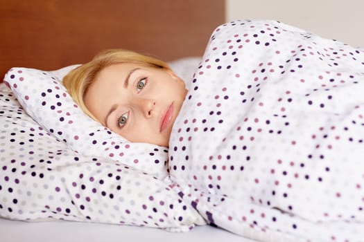 A young woman lying awake in her bed