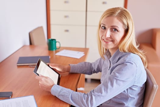 A young businesswoman working on her digital tablet at her desk