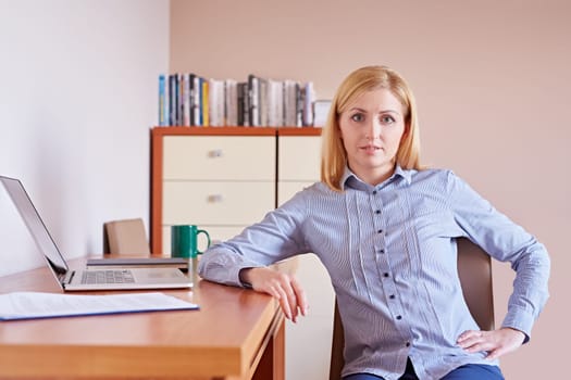 A young businesswoman smiling at the camera while sitting in her office