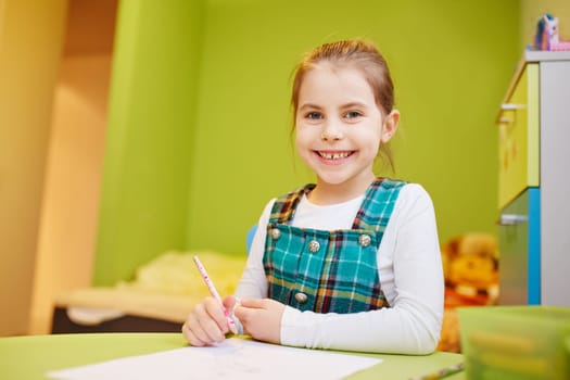 A little girl drawing in her room