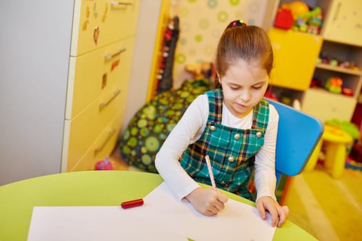 A little girl drawing in her room