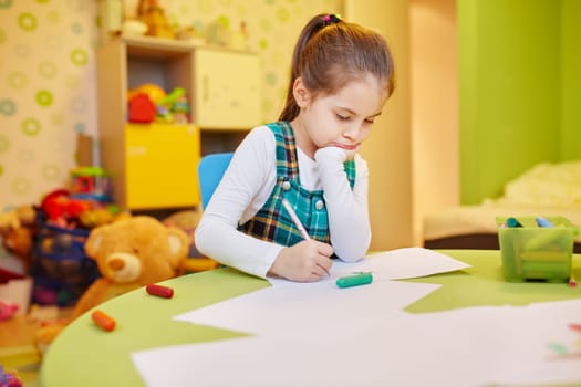 A little girl drawing in her room