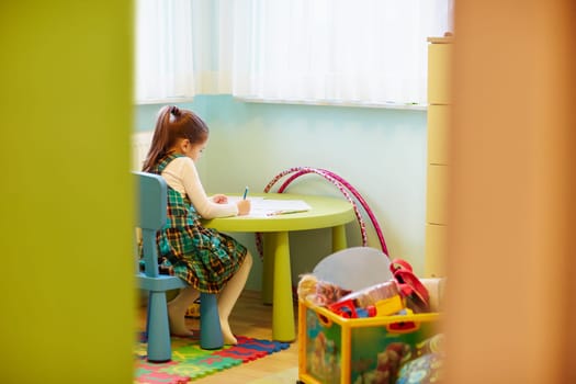 A little girl drawing quietly in her room