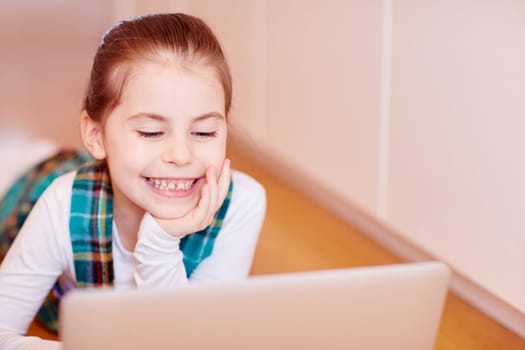 A cute little girl playing on a laptop