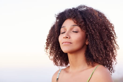 Beautiful mixed race woman with her eyes closed outdoors in a serene moment