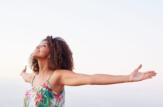 Beautiful mixed race woman expressing freedom with her arms outstretched outdoors