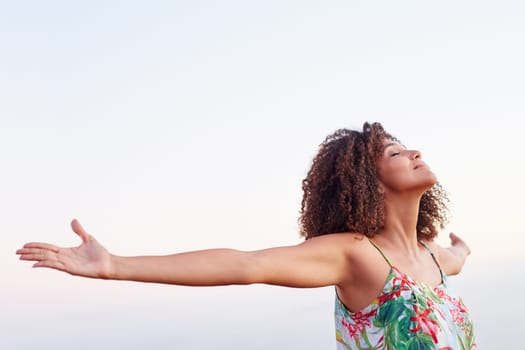 Woman outdoors with her arms outstretched and her eyes closed expressing serene freedom