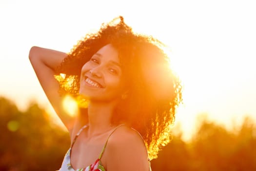 Closeup of a beautiful young woman with a sunset behind her