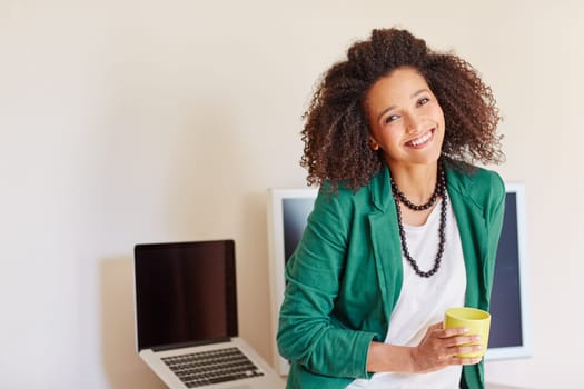 Mixed race businesswoman smiling while standing in front of her desk with a cup of coffee