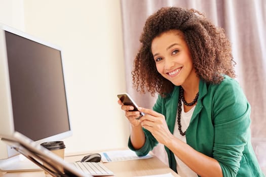 Beautiful young businesswoman sitting at her desk while making a call on her mobile phone