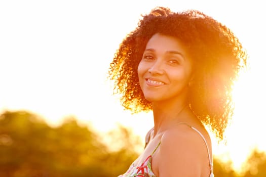Closeup of a beautiful young woman with a sunset behind her