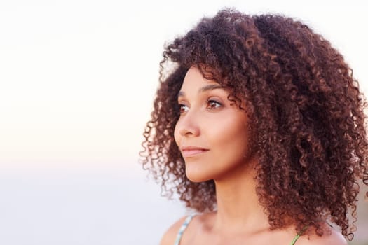 Beautiful mixed race woman with curly afro hair looking serenely away outdoors