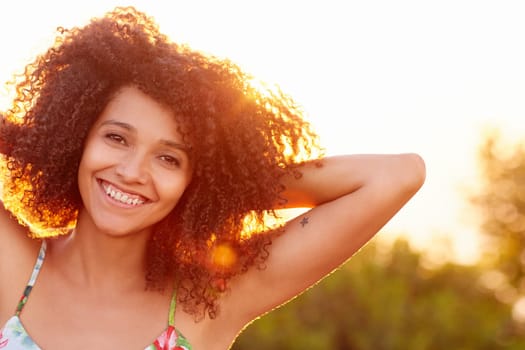 Closeup of a beautiful young woman with a sunset behind her