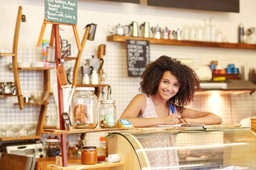 A young woman standing behind the counter in a coffee shop
