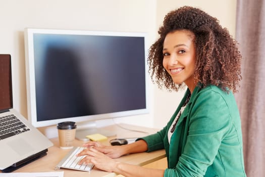 Beautiful young businesswoman is working on computer and looking in to the camera