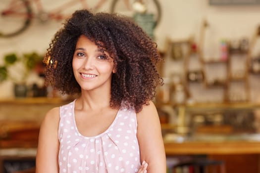 Closeup of a gorgeous mixed race woman with afro hair smiling at the camera in a coffee shop