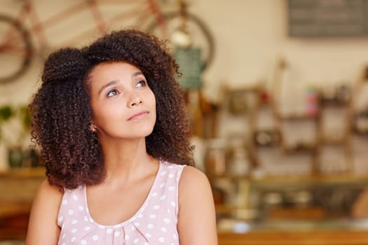 Mixed race woman in a coffee shop looking away thoughtfully and daydreaming