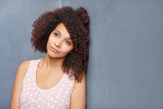 A young woman leaning against a gray wall
