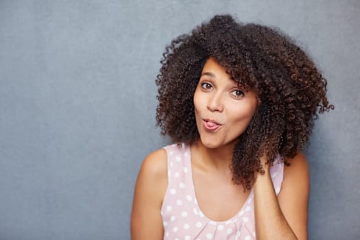 A young woman sticking her tongue out against a gray background