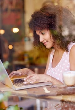 Beautiful young woman with an afro hairstyle working at her laptop in a coffee shop