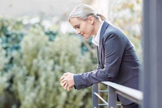 A young businesswoman leaning against the railing of her office balcony
