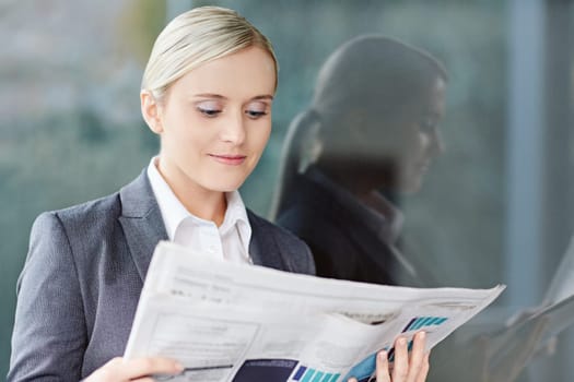 A young businesswoman reading the newpaper outside her office