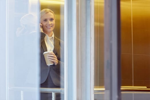 A young businesswoman talking on the phone in elevator