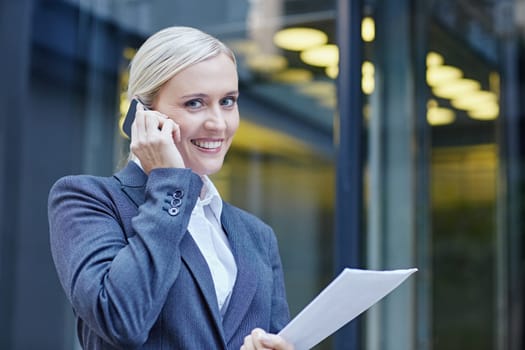 A young businesswoman talking on her cellphone outside