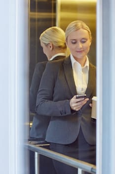 A young businesswoman texting someone in elevator
