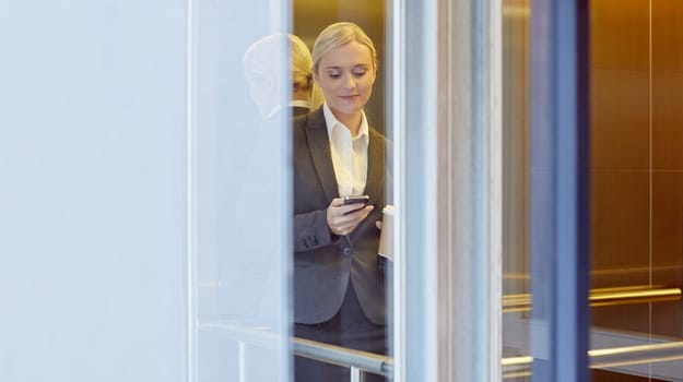 A young businesswoman texting someone in elevator