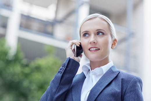 A young businesswoman talking on her cellphone outside