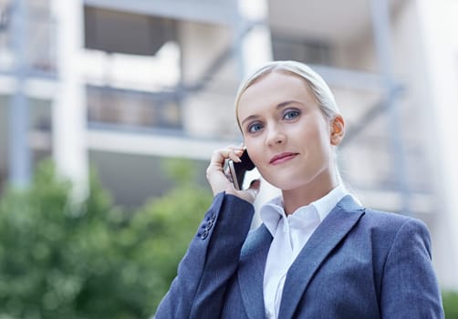 A young businesswoman talking on her cellphone outside
