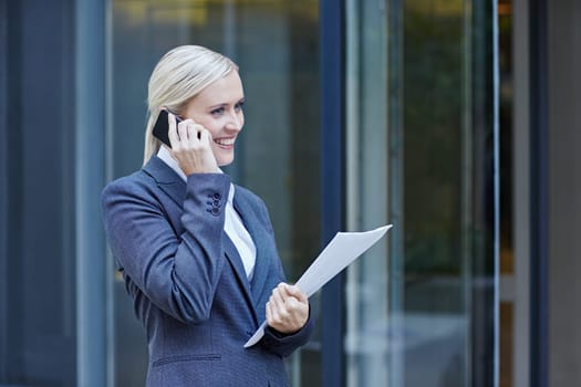 A young businesswoman talking on her cellphone outside