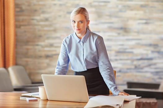 A young businesswoman at her desk, looking in to the camera