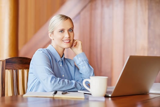 Portrait of a young businesswoman at her desk, looking and smiling in to the camera
