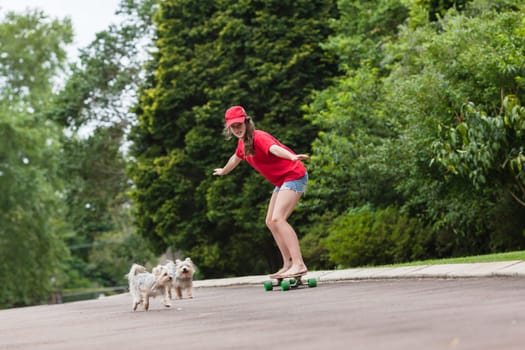 Girls skateboarding home driveway with dogs