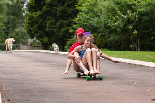 Girls skateboarding home driveway with dogs