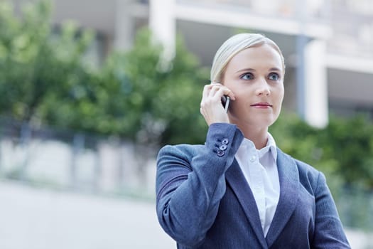 A young businesswoman talking on her cellphone outdoors