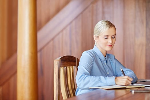 A young businesswoman taking notes, inside wooden office