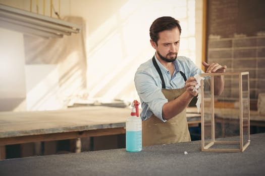 Craftsman designer concentrating while applying the finishing touches to a project in his woodwork workshop