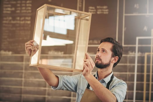 Designer looking carefully at a new product made from glass and wood in preparation for entrepreneurial marketing