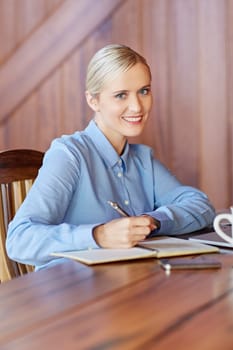 A young businesswoman taking notes in wooden office