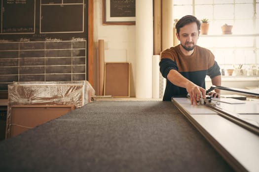 Young male designer working with concentration and using a tool at his workbench in his studio