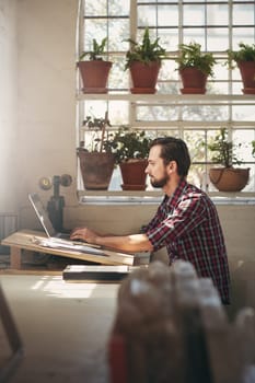 Young male entrepreneur working with concentration on his laptop while sitting in the office space of his design studio