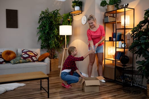 A heartwarming family scene showing two people joyfully unpacking a large box together in their cozy living room