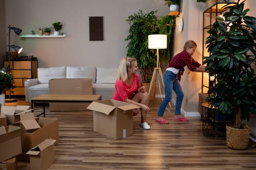 A loving mother and her excited daughter enjoy the fun of unpacking their boxes in their new cozy living space