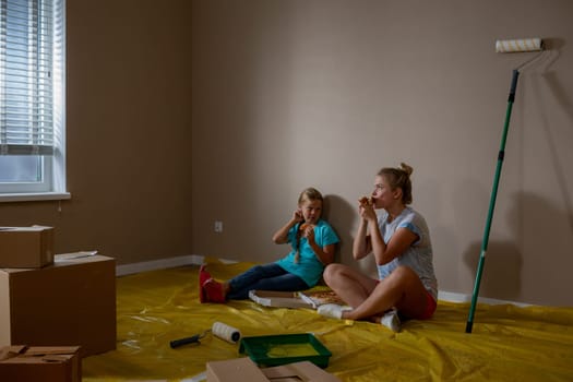 Two cheerful little girls are happily enjoying snacks together in a newly painted, vibrant living space